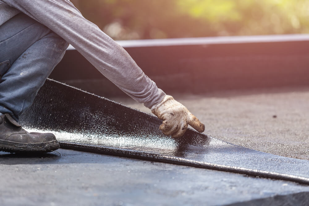 A commercial roofing technician installing a mod-bit roofing system