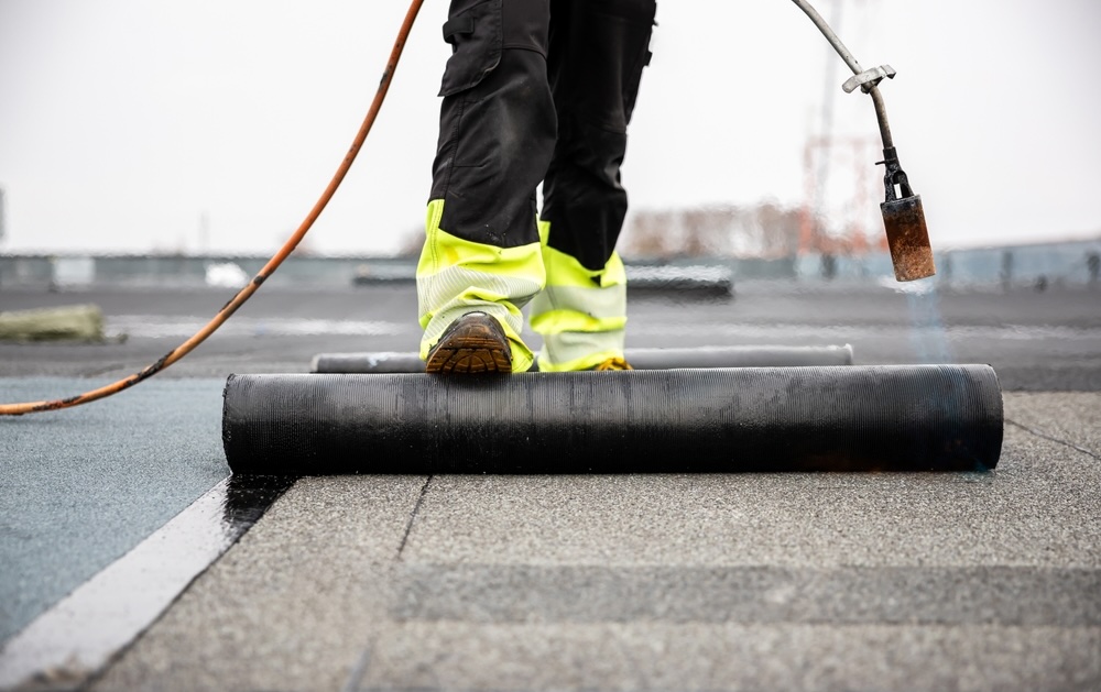 Professional,Roofer,Applying,Tar,With,Blowtorch,On,New,Roofing,Felt A technician torches down a modified bitumen roofing system