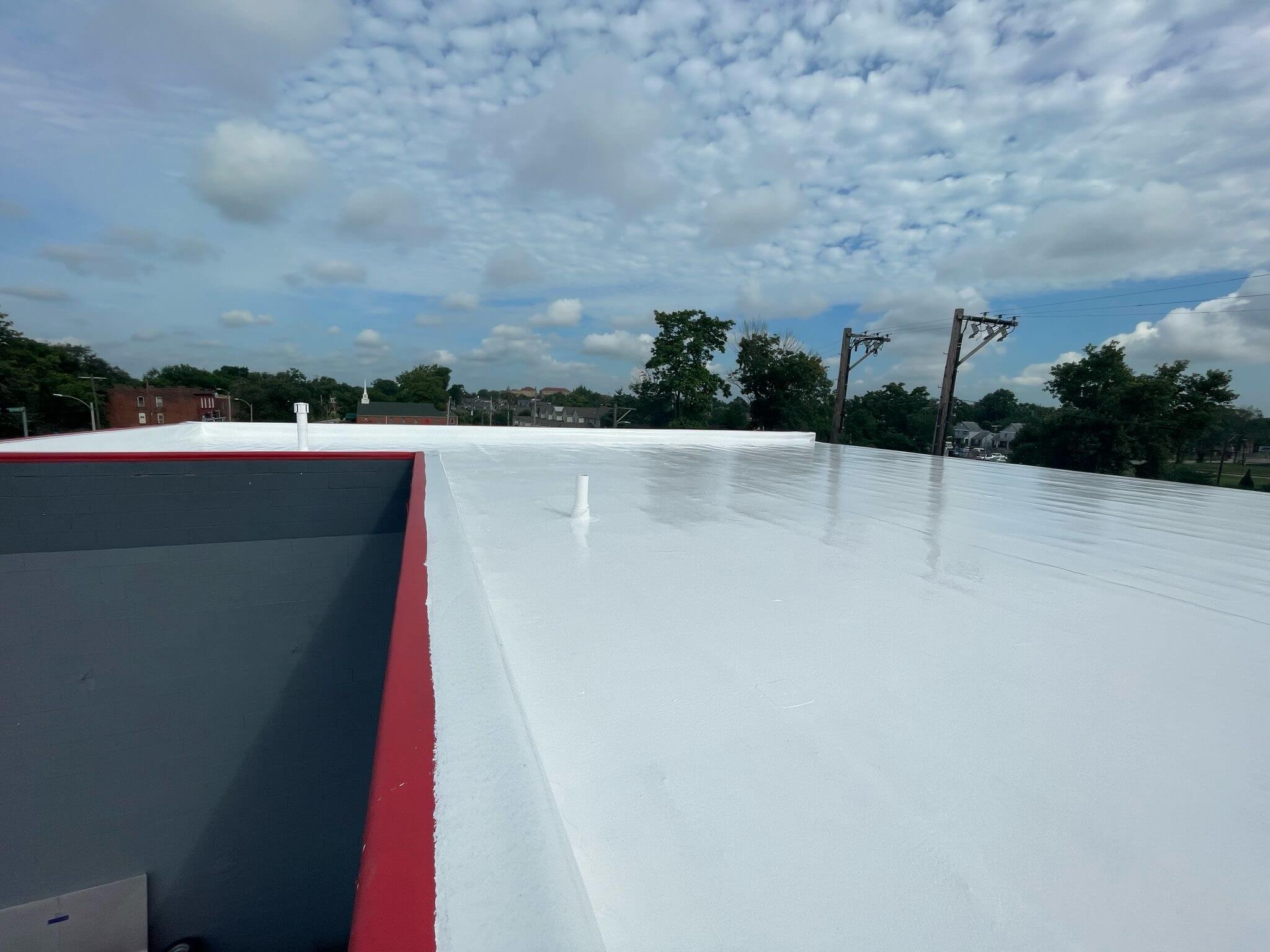 Commercial flat roof with TPO membrane, red trim, vents; ideal for flat roof restoration and maintenance.