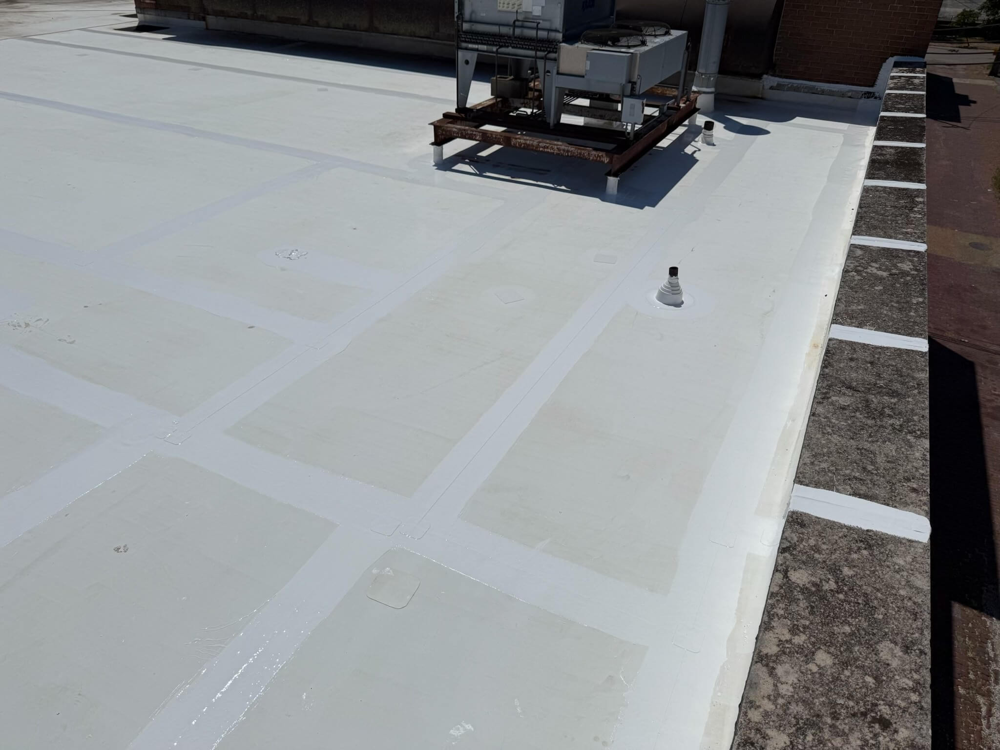 Commercial flat roof with white TPO coating, HVAC units, seams, and vent for flat roof restoration and maintenance.