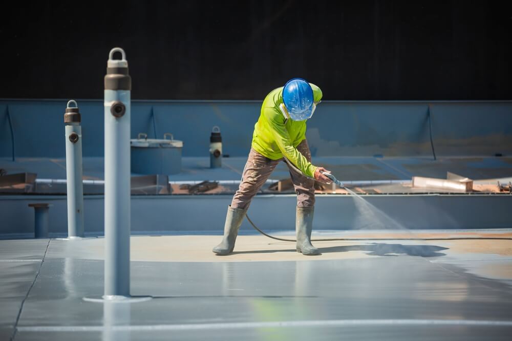 A roofing contractor applies a coating during a roof restoration