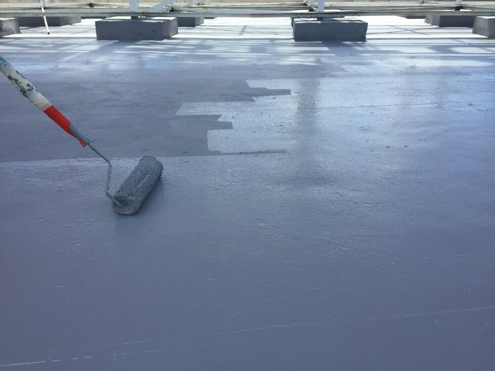 Close-up of a worker using a roller to apply elastomeric roof coating