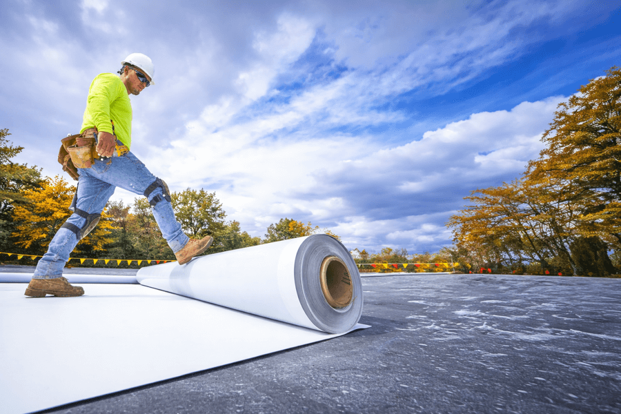 commercial-roof-overlay-membrane-installation-flat-roof-99 commercial roofing worker installing membrane during flat roof overlay system installation