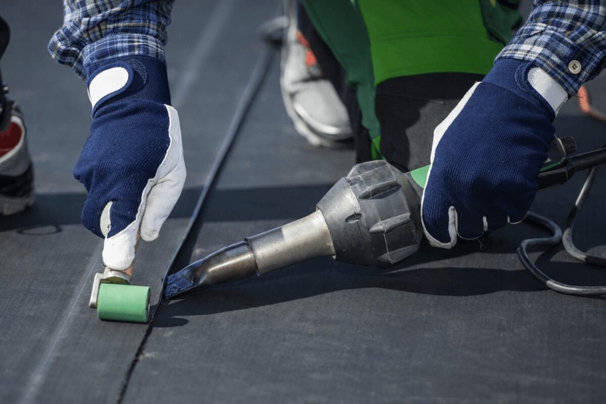 epdm-roof-seam-heat-welding-installation-98 Contractor sealing EPDM roofing seam using heat welding tool on flat roof