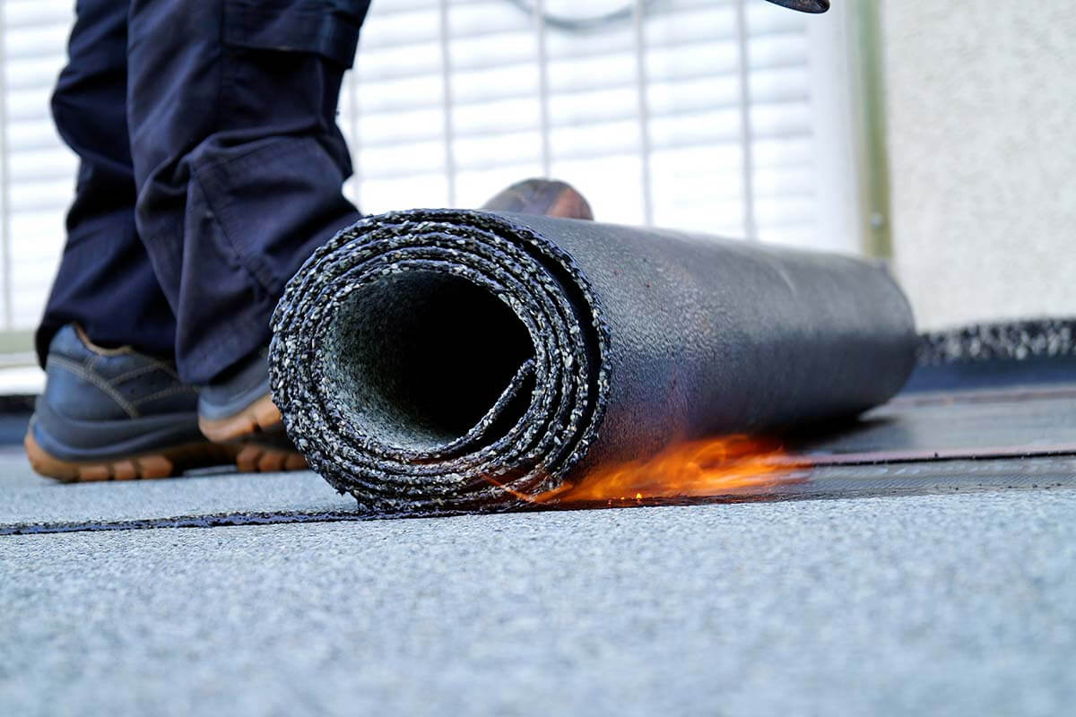 modified-bitumen-roof-roll-torch-application-98 Roll of modified bitumen roofing membrane being installed with torch application on flat roof