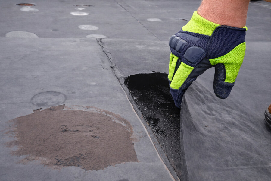 commercial-roof-membrane-seam-inspection-99 Close-up of a commercial roof membrane seam being inspected for damage and potential leaks