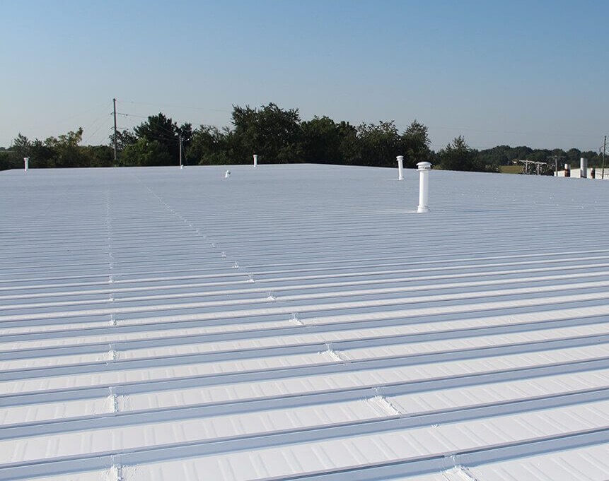 White silicone roof coating applied to a commercial metal roof to improve weather resistance and extend roof lifespan