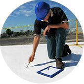 img-metal-roof-inspection Technician in a blue hard hat inspects TPO flat roof for commercial roof repair.