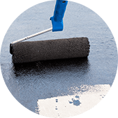 img-roof-coating A paint roller applies black coating during commercial flat roof restoration.