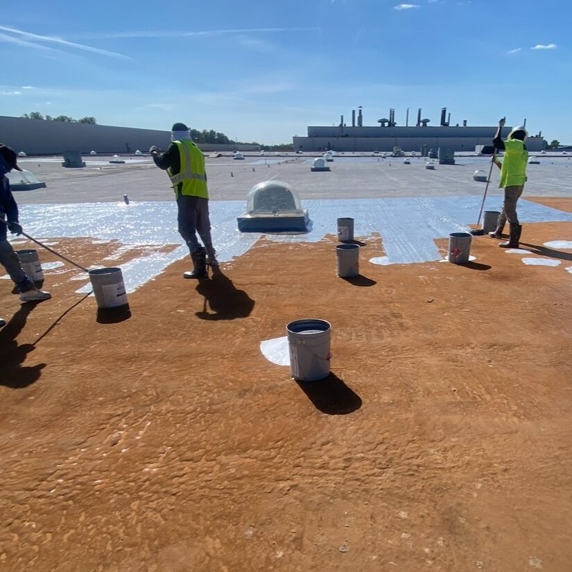 Screenshot Three workers in safety vests perform flat roof restoration with white coating.
