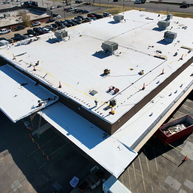 total-roof-replacement- Aerial view of TPO flat roof commercial building with ongoing flat roof restoration.